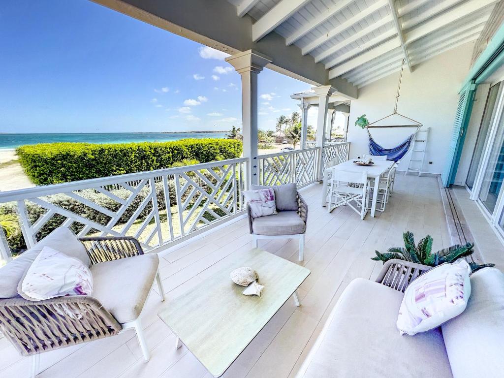 - une terrasse couverte dotée d'un mobilier blanc et offrant une vue sur l'océan dans l'établissement Princess Anouk Beachfront Orient Bay Deluxe 3 BDR, à La Baie-Orientale