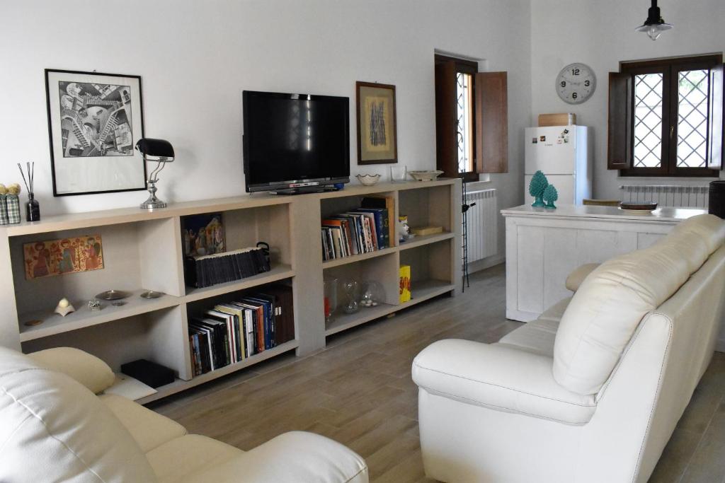 a living room with two white couches and a tv at Le Radici Home in LʼAquila