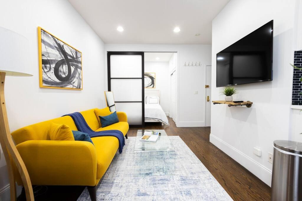 69-2D Stylish Lower East Side 1BR Apt BRAND NEW في نيويورك: غرفة معيشة مع أريكة صفراء وتلفزيون