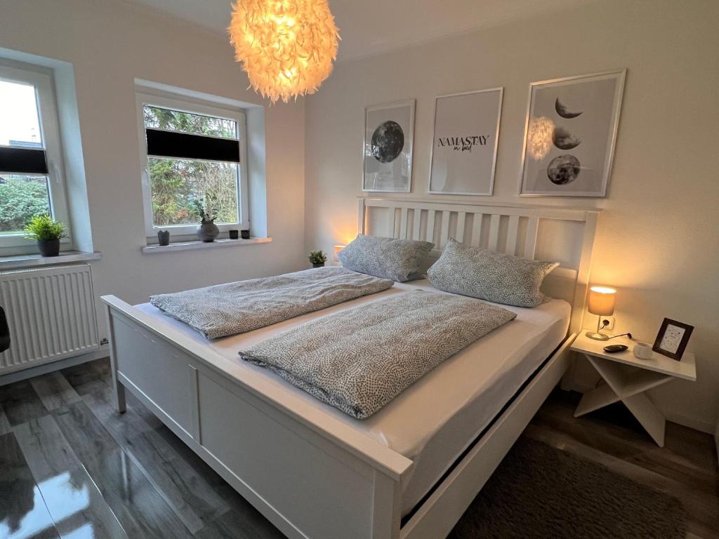 a bedroom with a large white bed with a chandelier at Unterwegs an der Nordsee in Wilhelmshaven