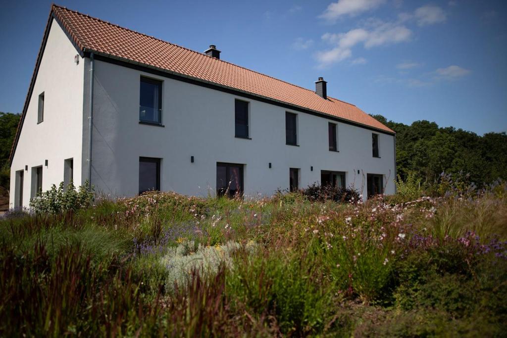 ein weißes Gebäude mit rotem Dach auf einem Feld in der Unterkunft Gîte XXV House - 8 personnes in Héron