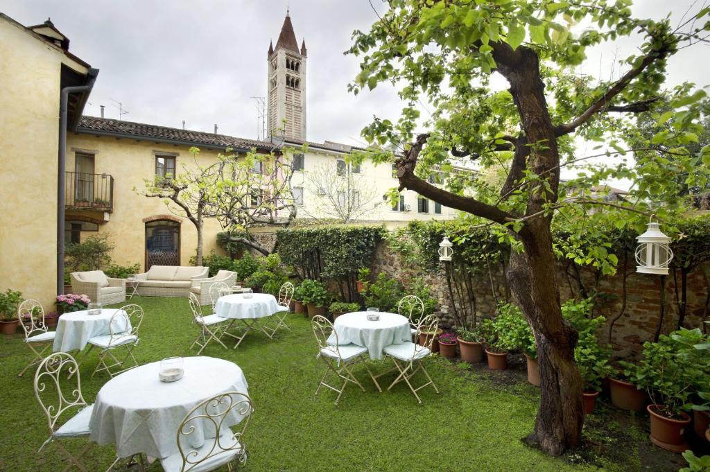 un giardino con tavoli e sedie bianchi e un edificio di Il Relais dell'Abbazia a Verona