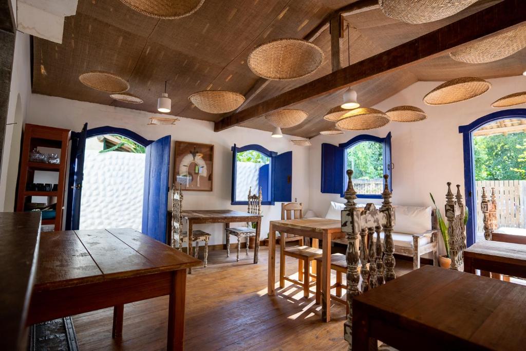 a dining room with wooden tables and chairs and windows at Arandu Casa Hotel Quadrado in Trancoso