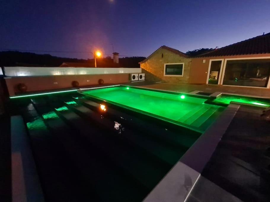a swimming pool with green lighting at night at Casa do Moleiro in Mortágua