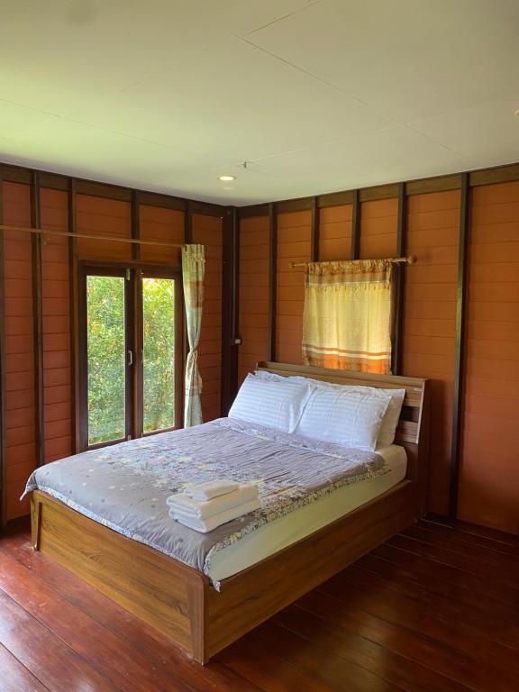 a bedroom with a bed with wooden walls and a window at Mookdaman Bungalow in Ko Yao Noi