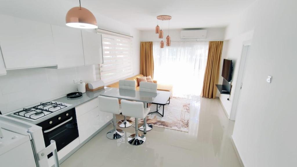 a white kitchen with a table and a stove at Rufus Brand New Caesar Resort & Spa 1 Bedroom Apartment with big terrace in Iskele