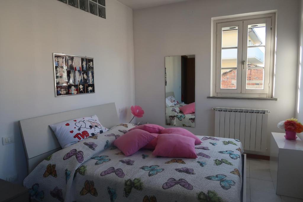 um quarto com uma cama com almofadas cor-de-rosa e uma janela em La casa di Ale em Arezzo