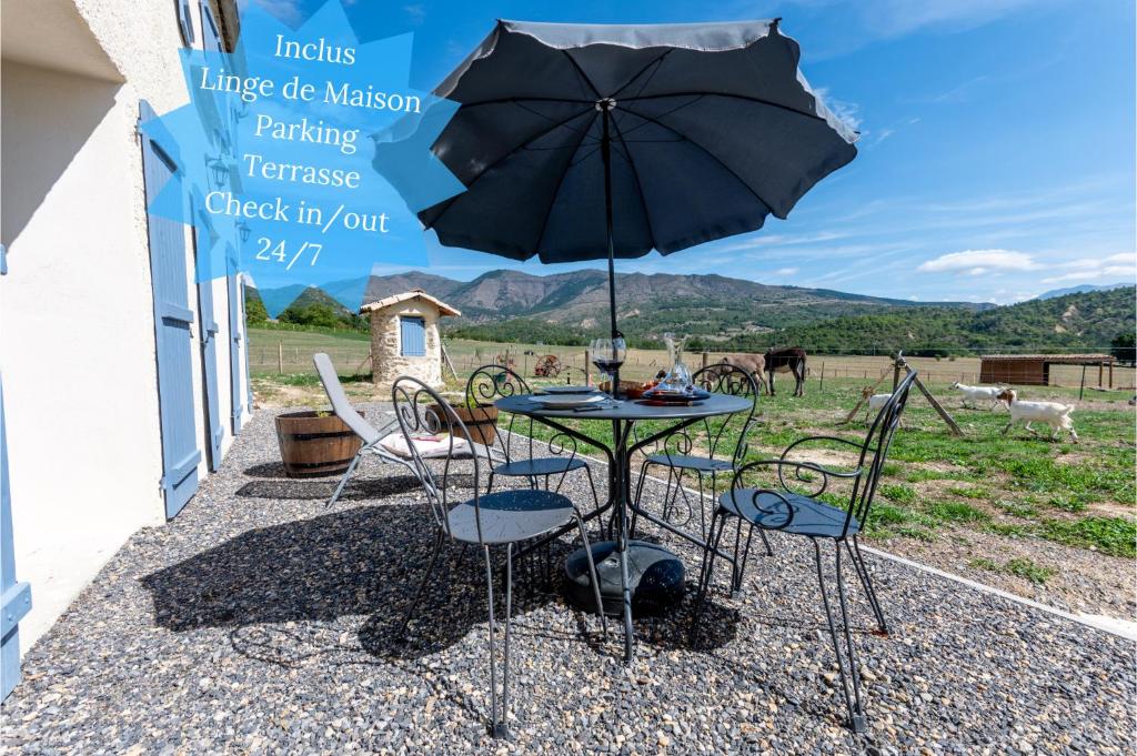 a table and chairs with an umbrella on a patio at Plaines-Provence Spa&Sauna in Digne-les-Bains