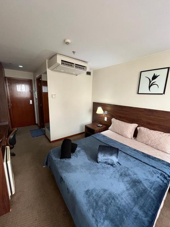 a bedroom with a large bed with a blue blanket at Flat em Taguatinga in Taguatinga