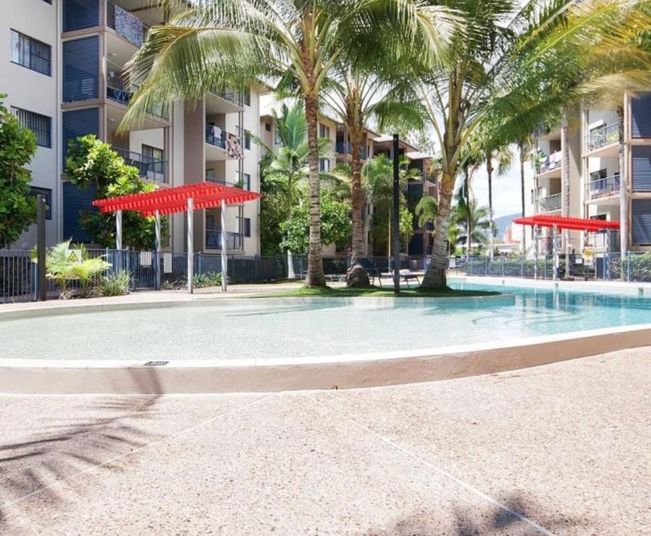 een zwembad met palmbomen en rode parasols bij 3 bedroom 2 bath apartment in Cairns Queensland in Cairns
