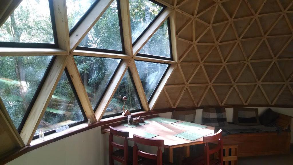 um quarto com uma mesa de madeira num quarto com janelas em Domo del bosque em Dalcahue