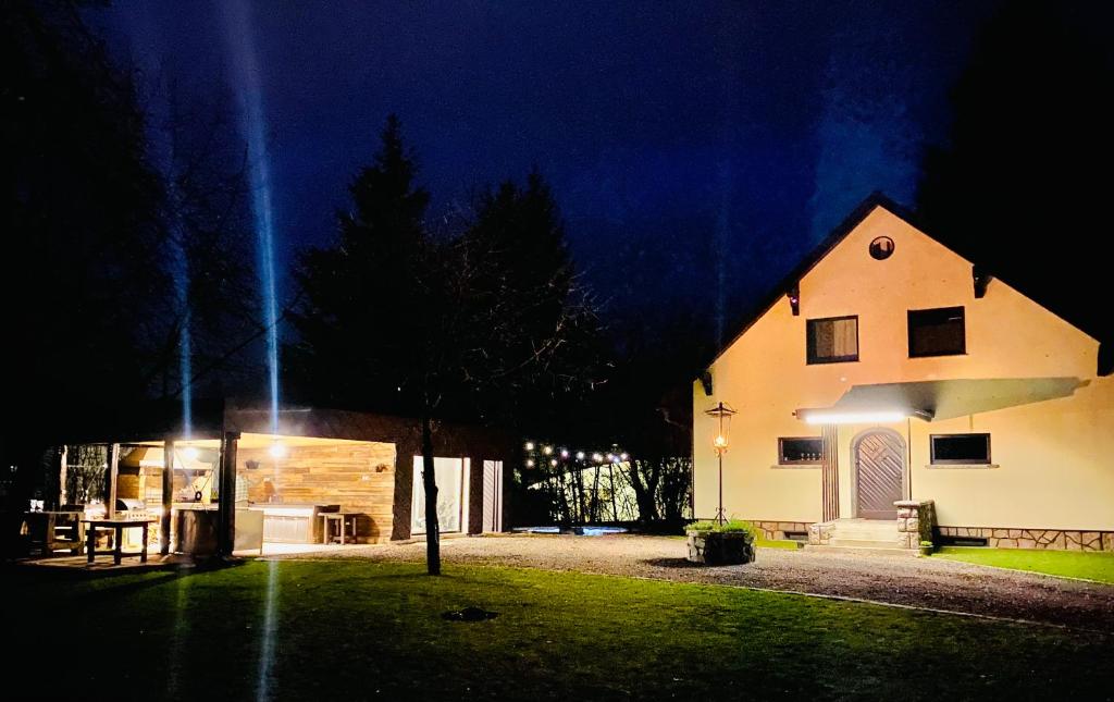 un gran edificio blanco por la noche con una casa en Vila Park Ravne, en Ravne na Koroškem