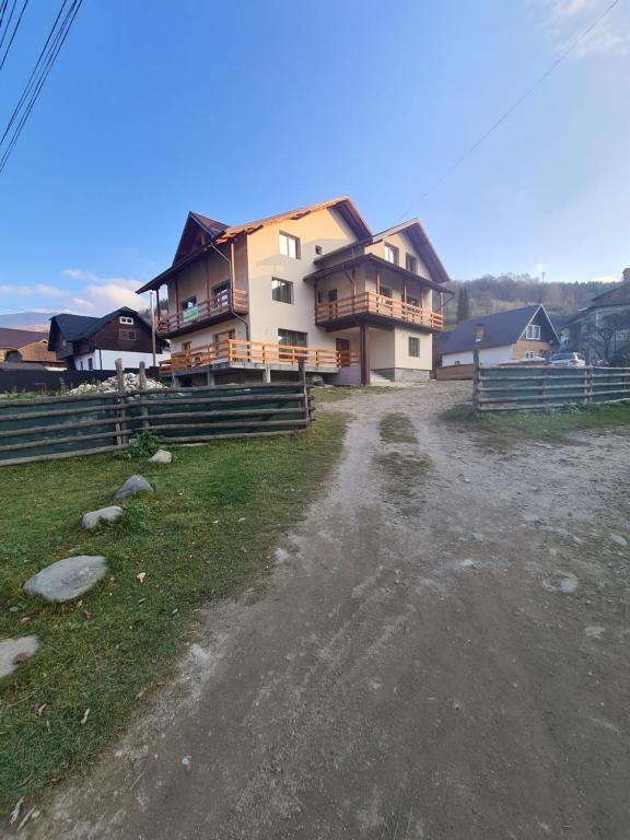 een groot huis met een onverharde weg ervoor bij Casa Bujor de Munte Dragoslavele in Dragoslavele