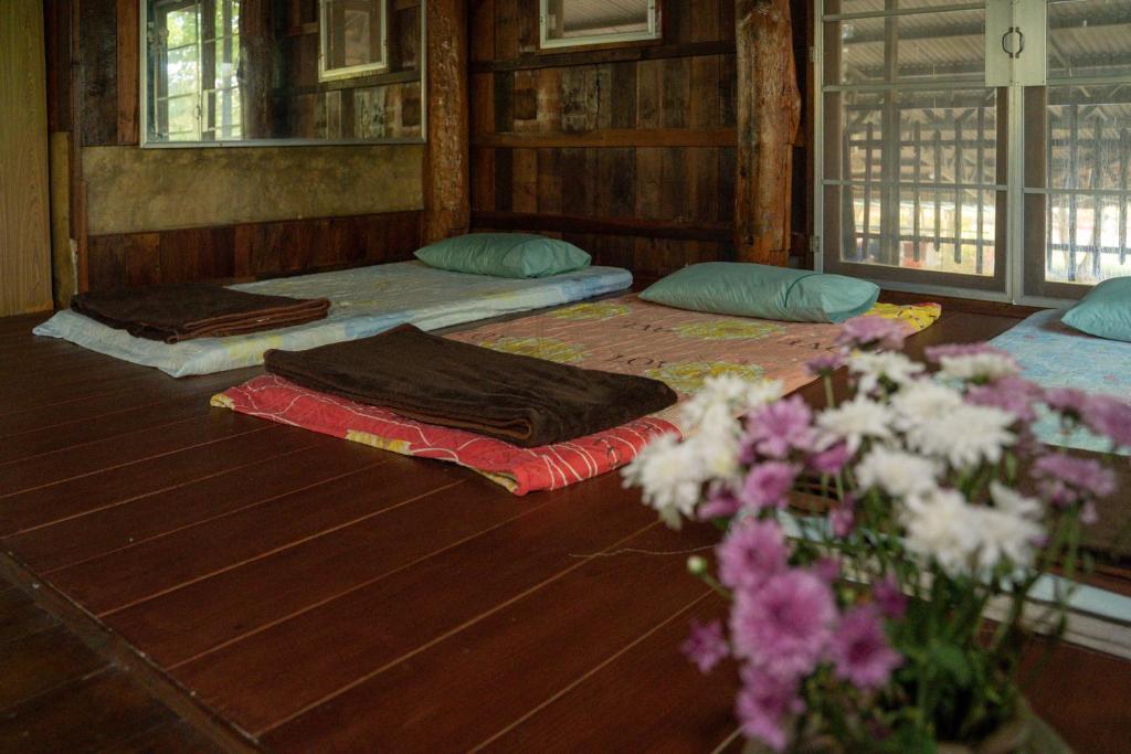チェンダオにあるArt House at Chiangdao - Waterlily Houseの花の飾られたフロアにベッド3台が備わる部屋