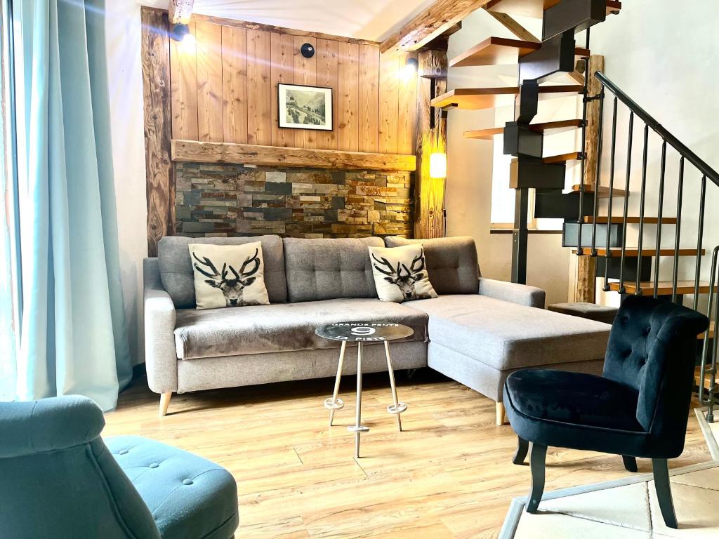 een woonkamer met een bank en een stoel bij La Grange Auguste avec Sauna Jacuzzi in Vénosc