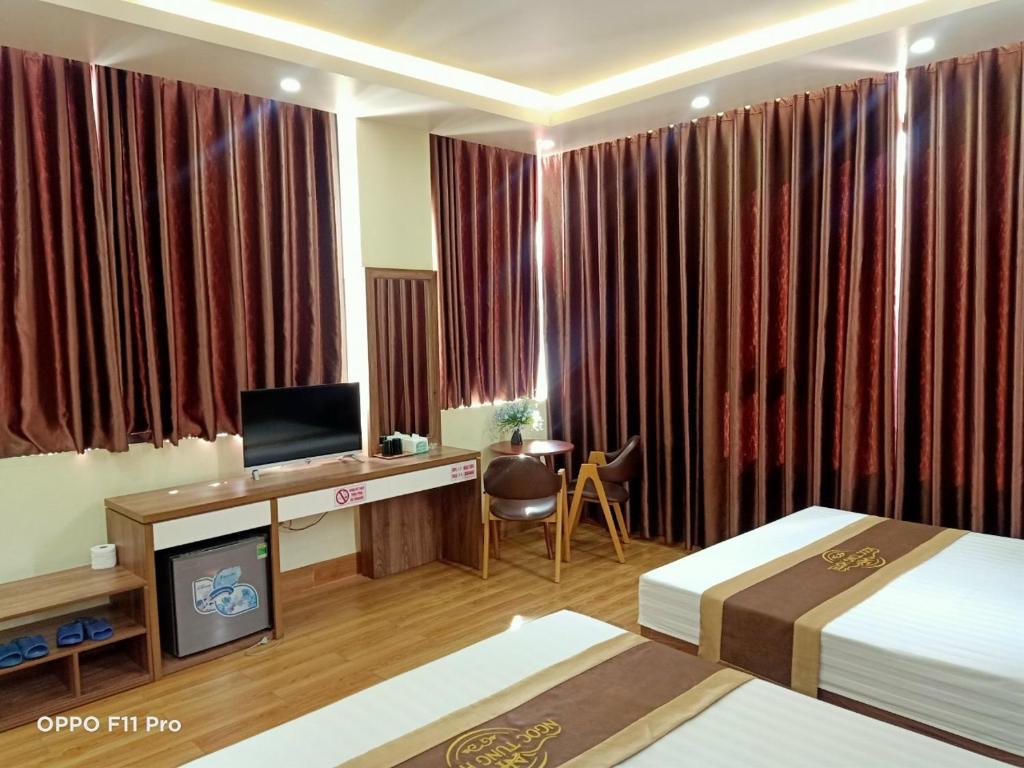 a hotel room with two beds and a desk with a television at Ngọc Tùng Hotel in Ha Long