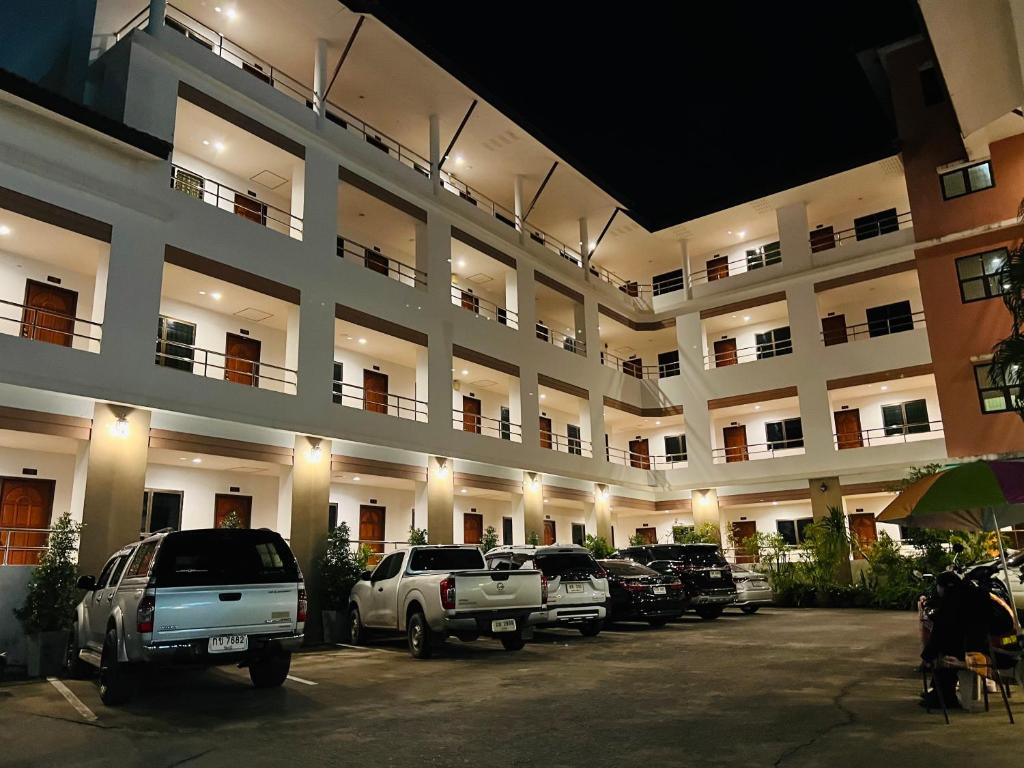 a large building with cars parked in a parking lot at JJ Palace เจเจ พาเลซ in Ban Si Than