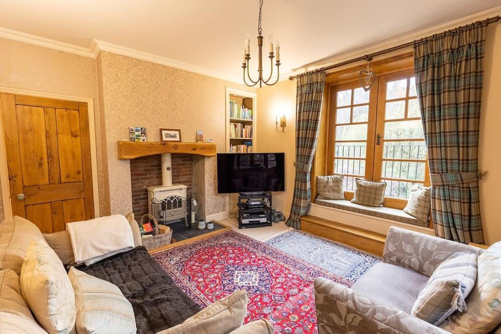 a living room with a couch and a fireplace at STATION COTTAGE - Unique Accommodation with River Flowing through Garden in Bolton Abbey