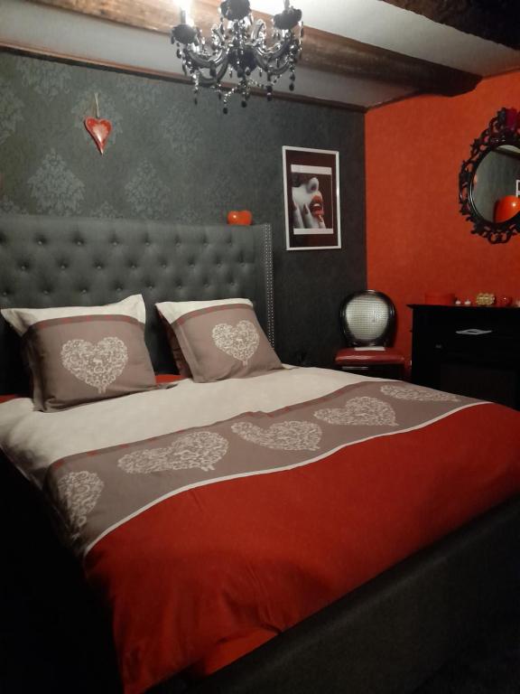 Un dormitorio con una cama con paredes rojas y una lámpara de araña. en LOVE ROOM Le rouge et noir, en Barr