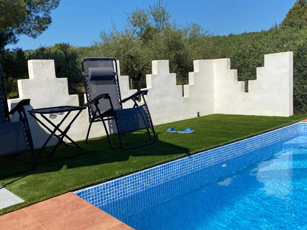 einen Pool mit zwei Stühlen und einem Tisch neben einem Zaun in der Unterkunft LO TROS in Botarell