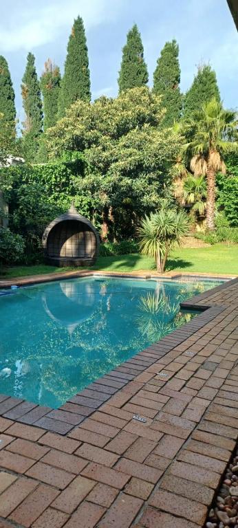 a swimming pool in a garden with trees in the background at Matina Guest House in Johannesburg