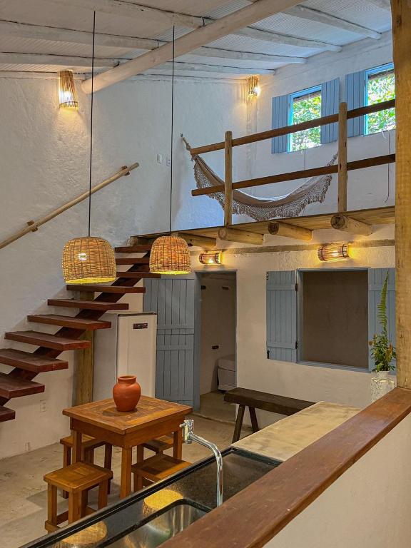a room with stairs and a table and a hammock at Casinha do Rio in Caraíva