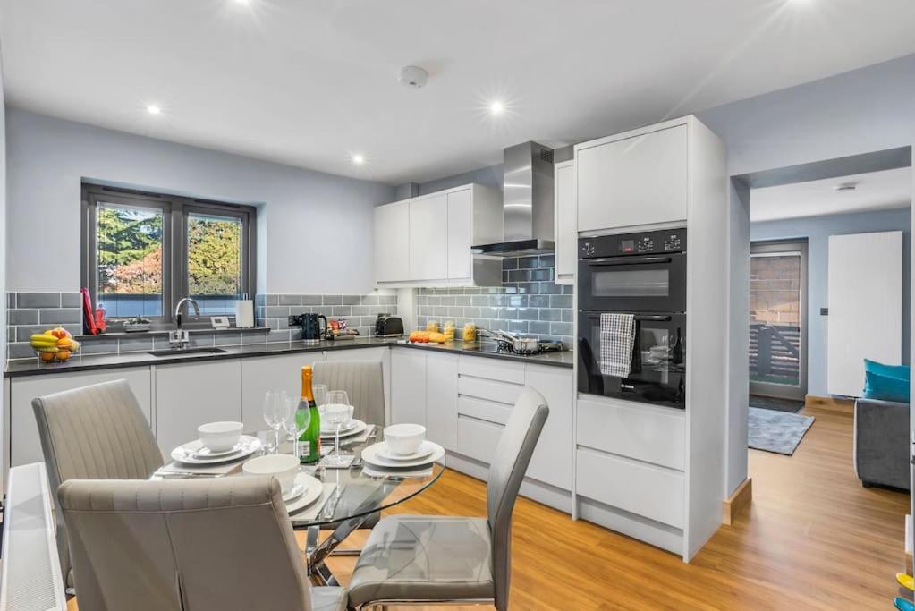 a kitchen with white cabinets and a table and chairs at Isabel’s wing! A stunning 2 bedroom annex in Norwich
