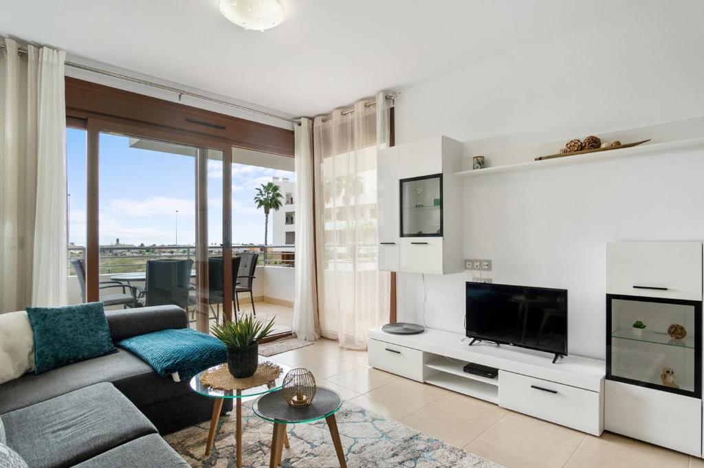 ein Wohnzimmer mit einem Sofa und einem TV in der Unterkunft CB Living - Modern apartment, Terrazas de Campoamor in Orihuela