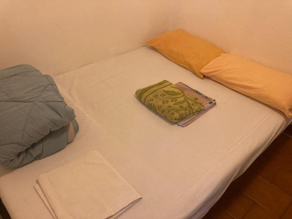 een wit bed met een kussen en een boek erop bij Cheerful Room, Sharing kitchen in a Cosy Family Art House, Ideal for one person or couple in Sanremo