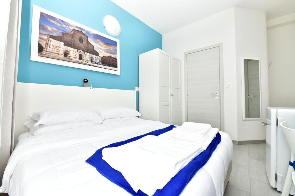 Cama blanca en habitación con pared azul en A San Lazzaro Rooms, en San Lazzaro di Savena