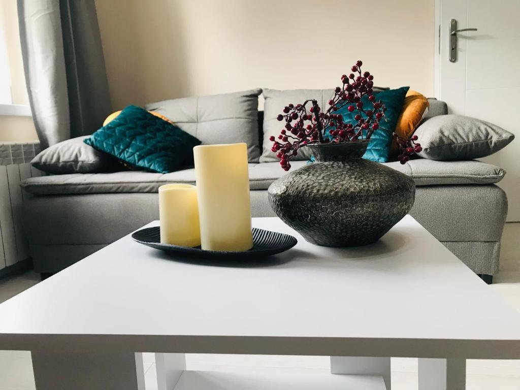 - une table basse blanche avec un vase et deux bougies dans l'établissement Apartament Vistula Centrum 4, à Wisła