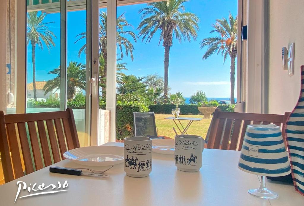 a dining table with a view of the ocean at Sunrise Estudio Picasso, con vistas jardín y mar in Miami Platja