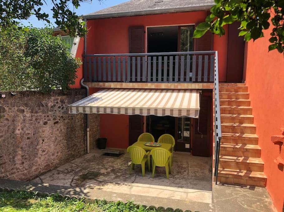 un patio avec une table et des chaises devant une maison dans l'établissement Joli appartement avec terrasse et jardin - vue sur montagne, à Bagnères-de-Bigorre
