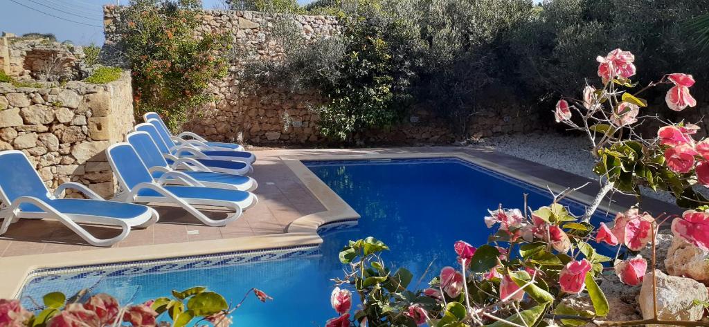 a group of chairs sitting next to a swimming pool at Ta’ Peppi Farmhouse in Qala