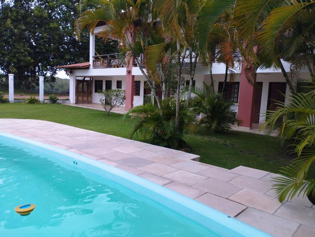 a house and a swimming pool in front of a house at Pousada São Nunca in Ilha de Comandatuba