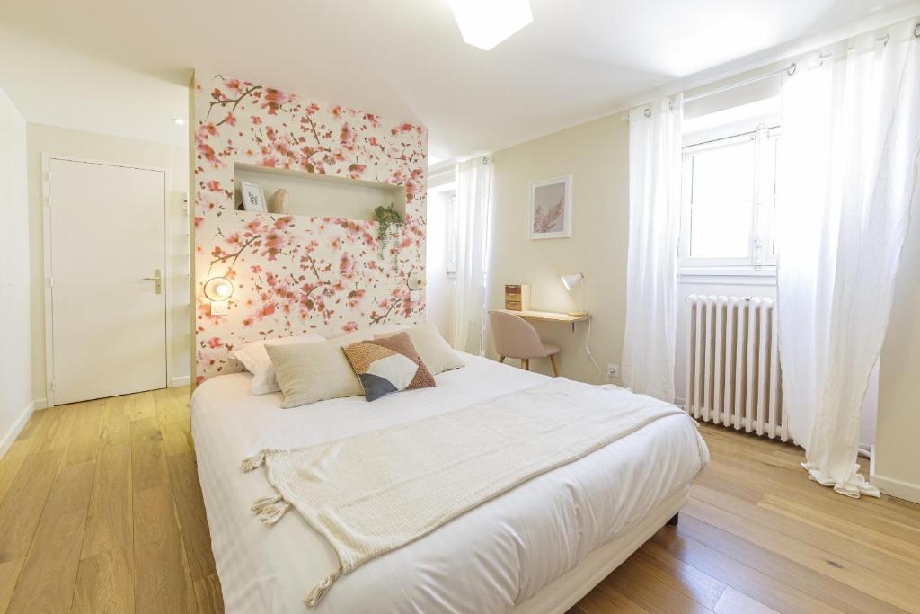 una camera da letto con un grande letto bianco con una parete floreale di Maison Bossoreil - Chambre Crémant ad Angers