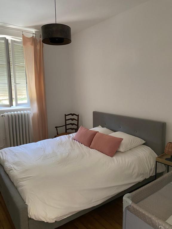 una camera con un letto bianco con due cuscini rosa di Maison chaleureuse avec piscine 