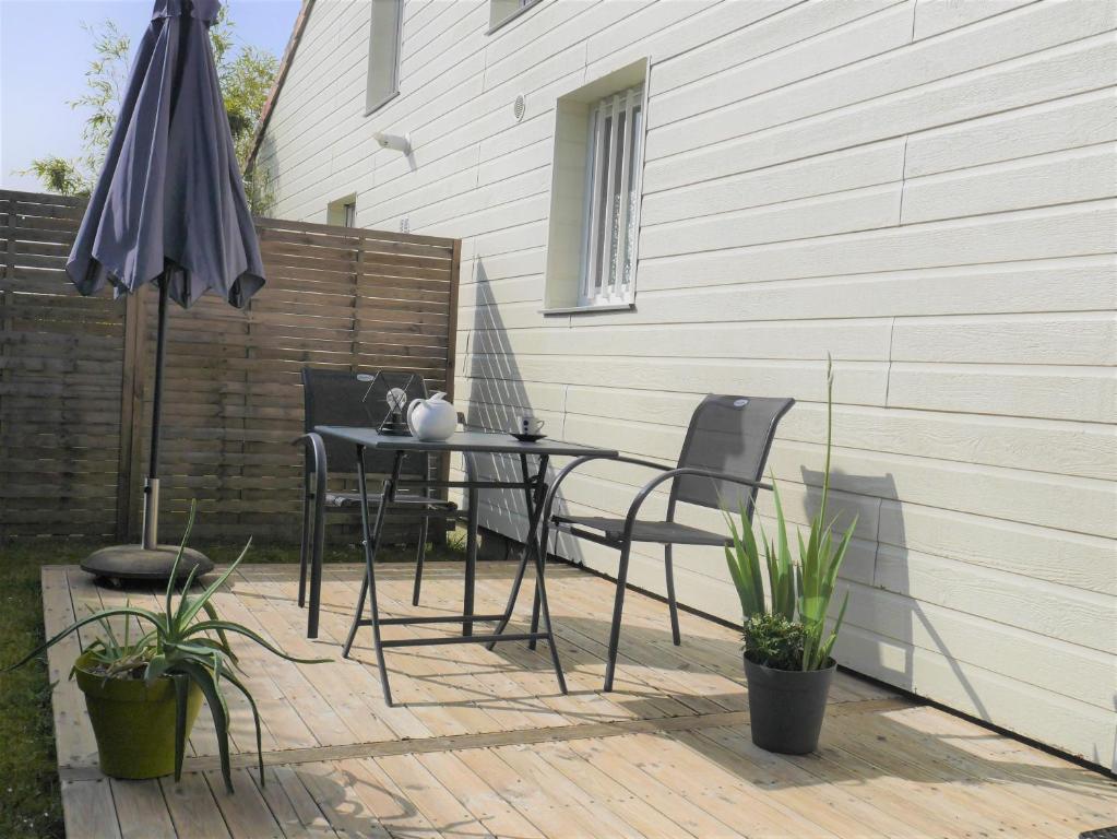 eine Terrasse mit einem Tisch, Stühlen und einem Sonnenschirm in der Unterkunft Studio de Fontaine in Fontaine-le-Comte