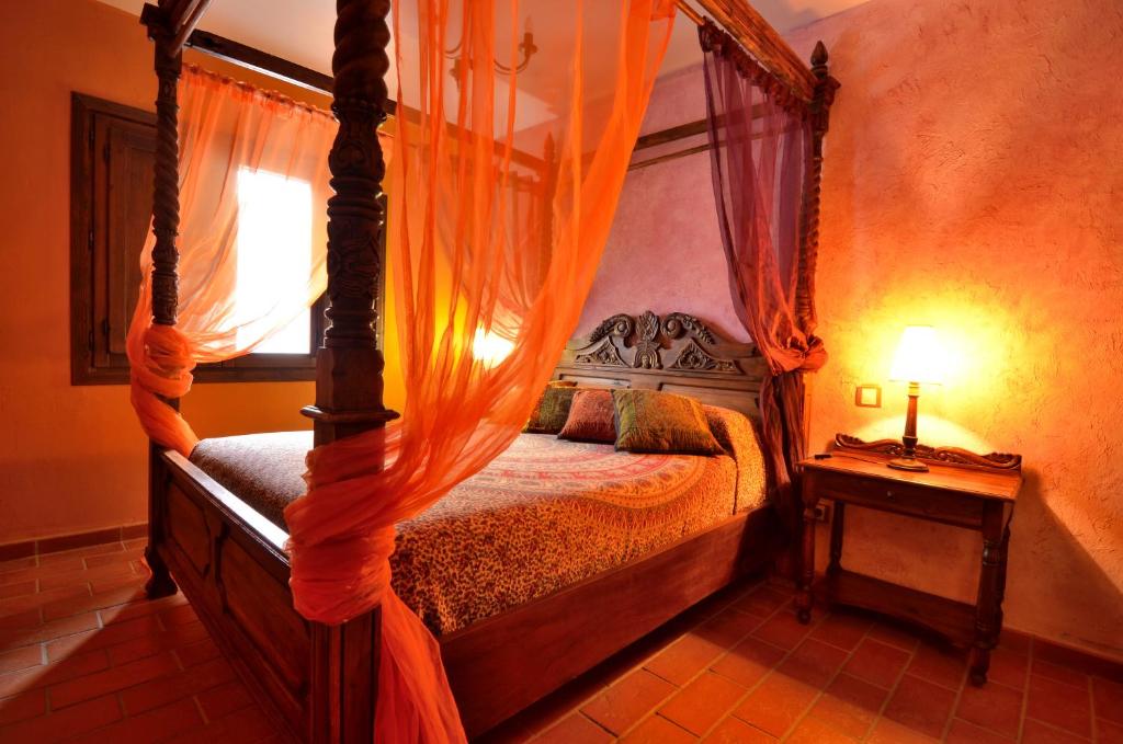 een slaapkamer met een hemelbed en een oranje gordijn bij Espacios Del Mundo in Carenas