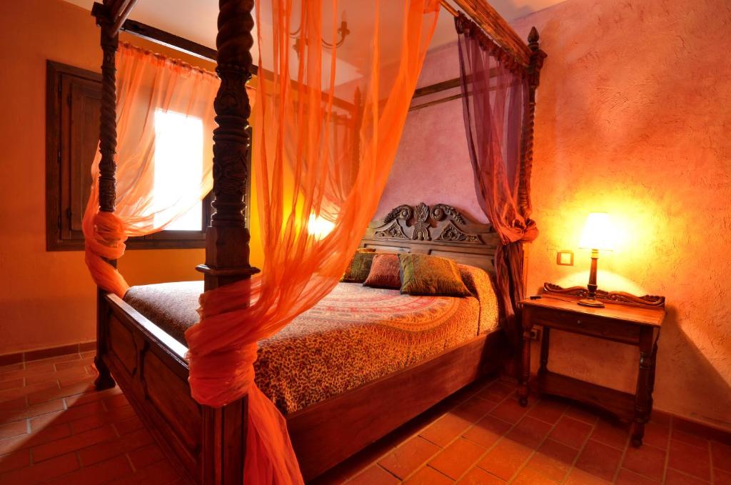 a bedroom with a canopy bed with an orange curtain at Espacios Del Mundo in Carenas