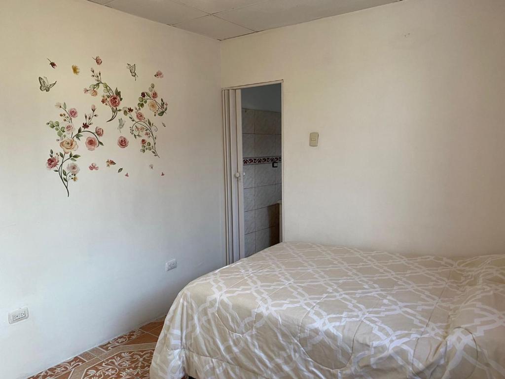 a bedroom with a bed and a flower mural on the wall at Los Tamarindos Posadamanabita in Portoviejo