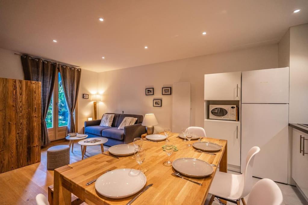 a kitchen and living room with a wooden table and chairs at Serre Chevalier Monêtier les Bains T3 jardin Appartement les Mélèzes in Le Monêtier-les-Bains