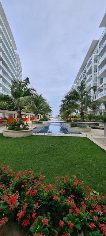 un complexe avec une piscine, des palmiers et des fleurs dans l'établissement Hermoso apartamento de lujo en Morros 3 , Piso 5 con vista al mar, à Carthagène des Indes