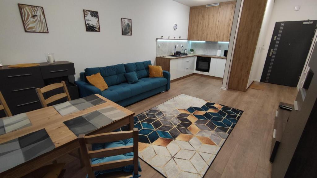 ein Wohnzimmer mit einem blauen Sofa und einem Tisch in der Unterkunft Apartament "Marianki" Jagiełły 3 in Świecie