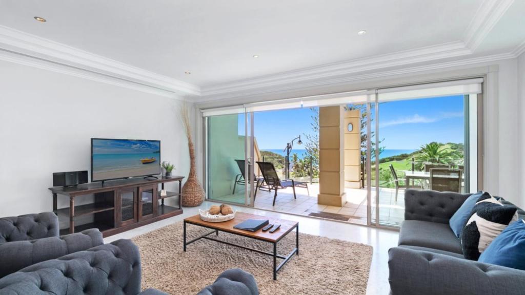 a living room with a couch and a tv at Unit 22 - 3 Bed Ocean View in Terrigal