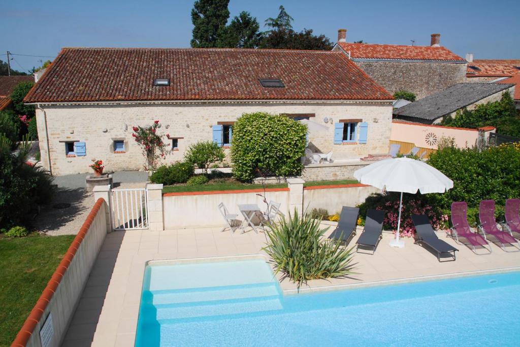 una piscina con sedie e ombrellone e una casa di Grand gîte jusqu'à 7 personnes, avec piscine a Corpe