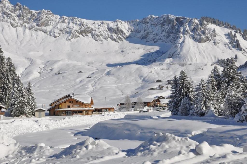 a snow covered mountain with a house in the foreground at Les Roches 1500 in Mieussy