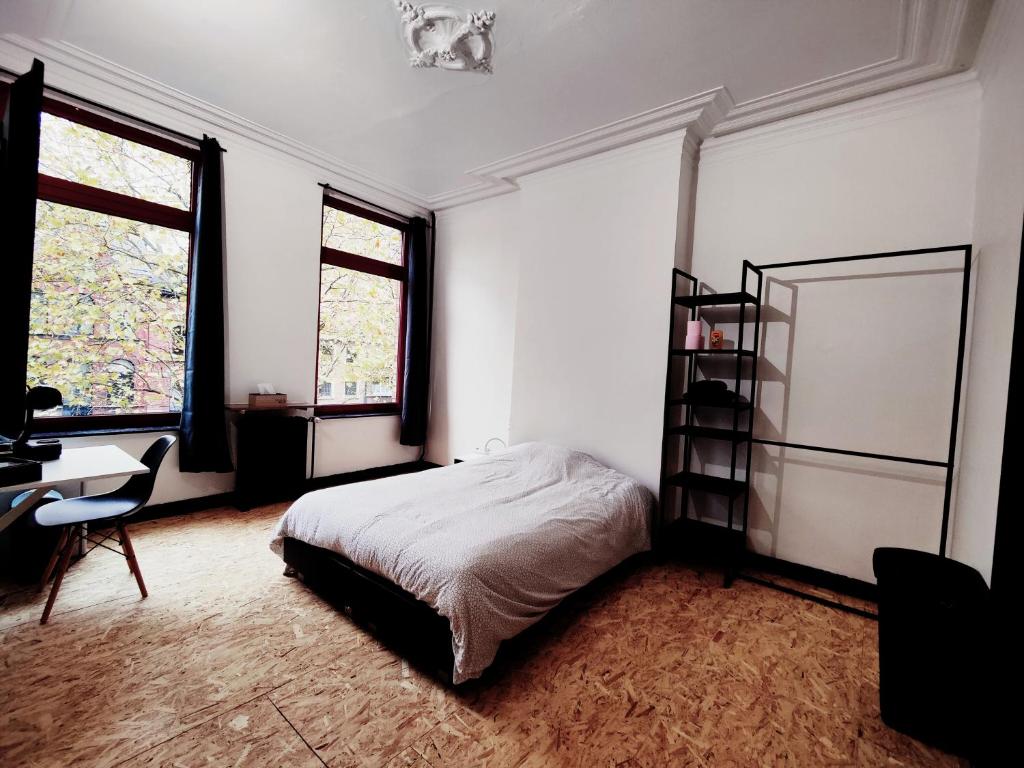 een slaapkamer met een bed, een bureau en 2 ramen bij Private industrial room 2 in center of Charleroi in Charleroi