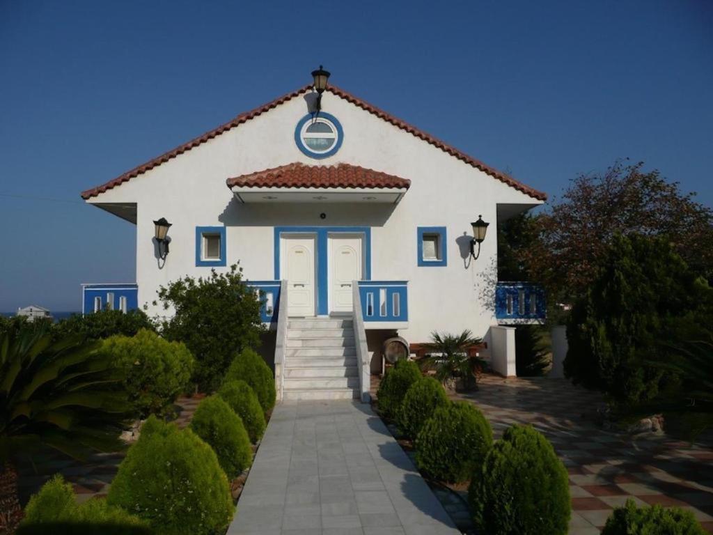 Una gran casa blanca con una puerta azul y escaleras en Megisti, en Mourteri