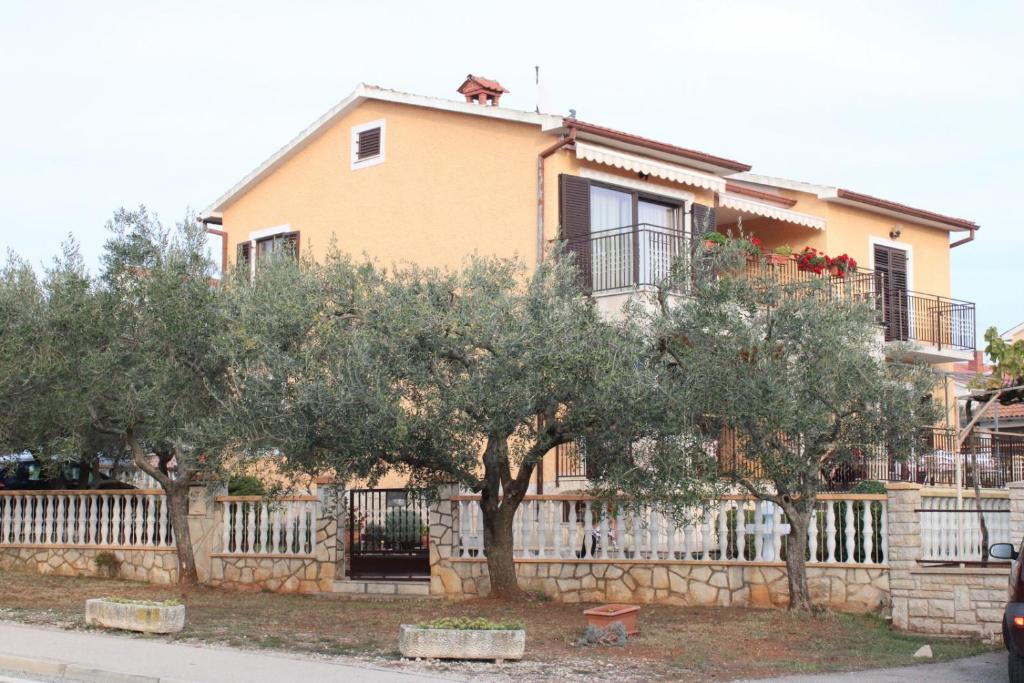 ein Haus mit einem Baum vor einem Zaun in der Unterkunft Lily's lovely apartments in Fažana